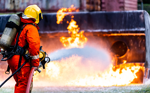 Firefighter using Chemical foam fire extinguisher to fighting with the fire flame from oil tanker truck accident. Firefighter safety disaster accident and public service concept.